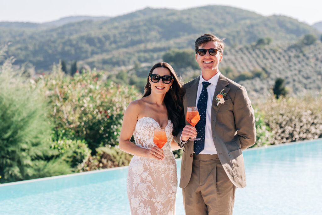 Ashley Miller Daniels and her husband enjoying Aperol Spritz cocktails by the pool during their wedding in Tuscany.