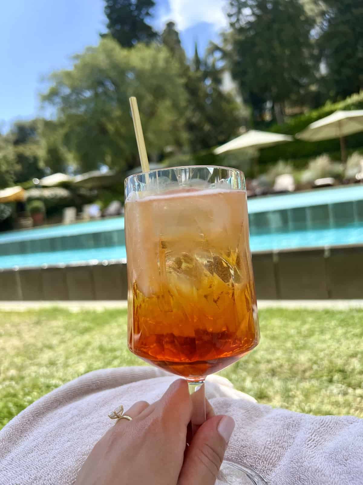 A vibrant Aperol Spritz served in a large wine glass overlooking the Tuscan countryside.