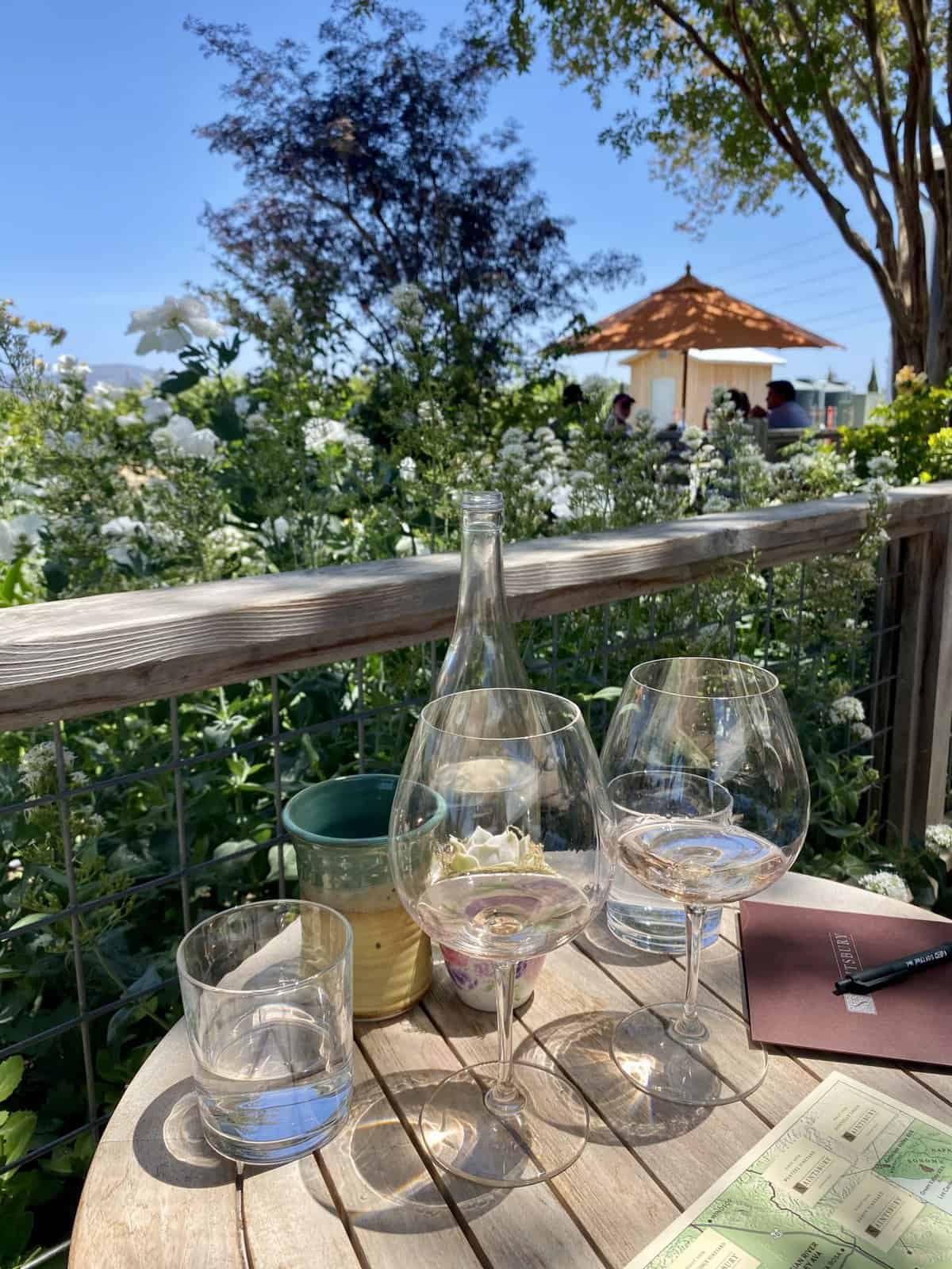 Wine glasses on a table in the garden of a winery called Saintsbury in Napa