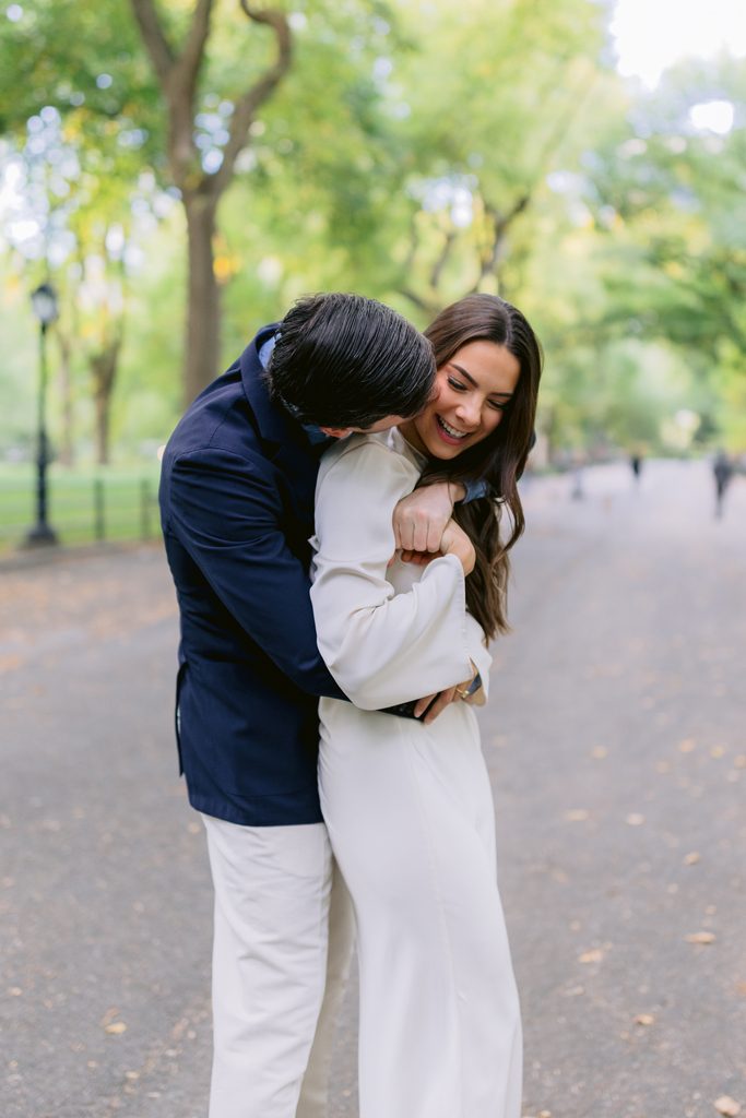 A quiet, hugging moment surrounded by the lush green landscape of Central Park in early October.