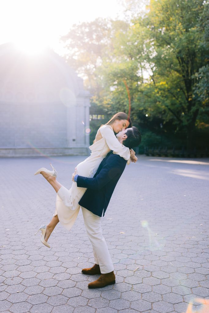 A romantic kiss in front of the historic Naumburg Bandshell, a classic architectural spot in Central Park.