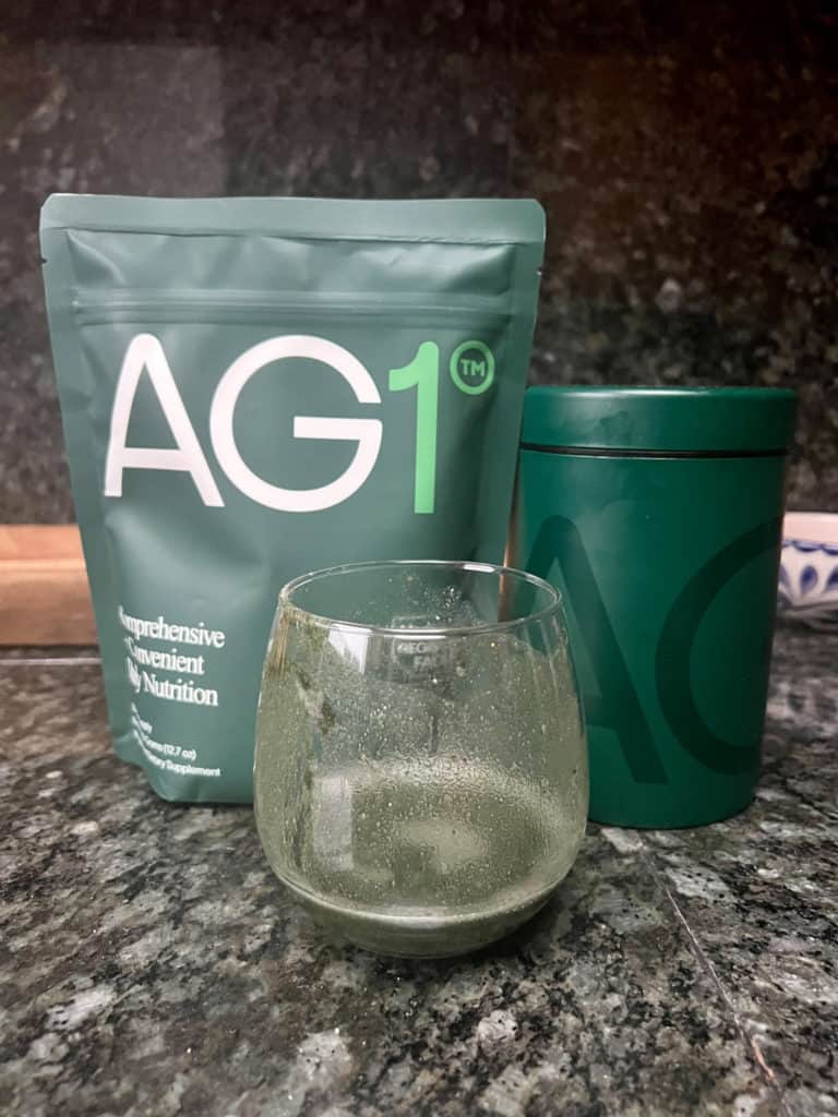 A close-up of the green AG1 liquid in a small glass, showing the smooth texture and mixability of the Athletic Greens powder.