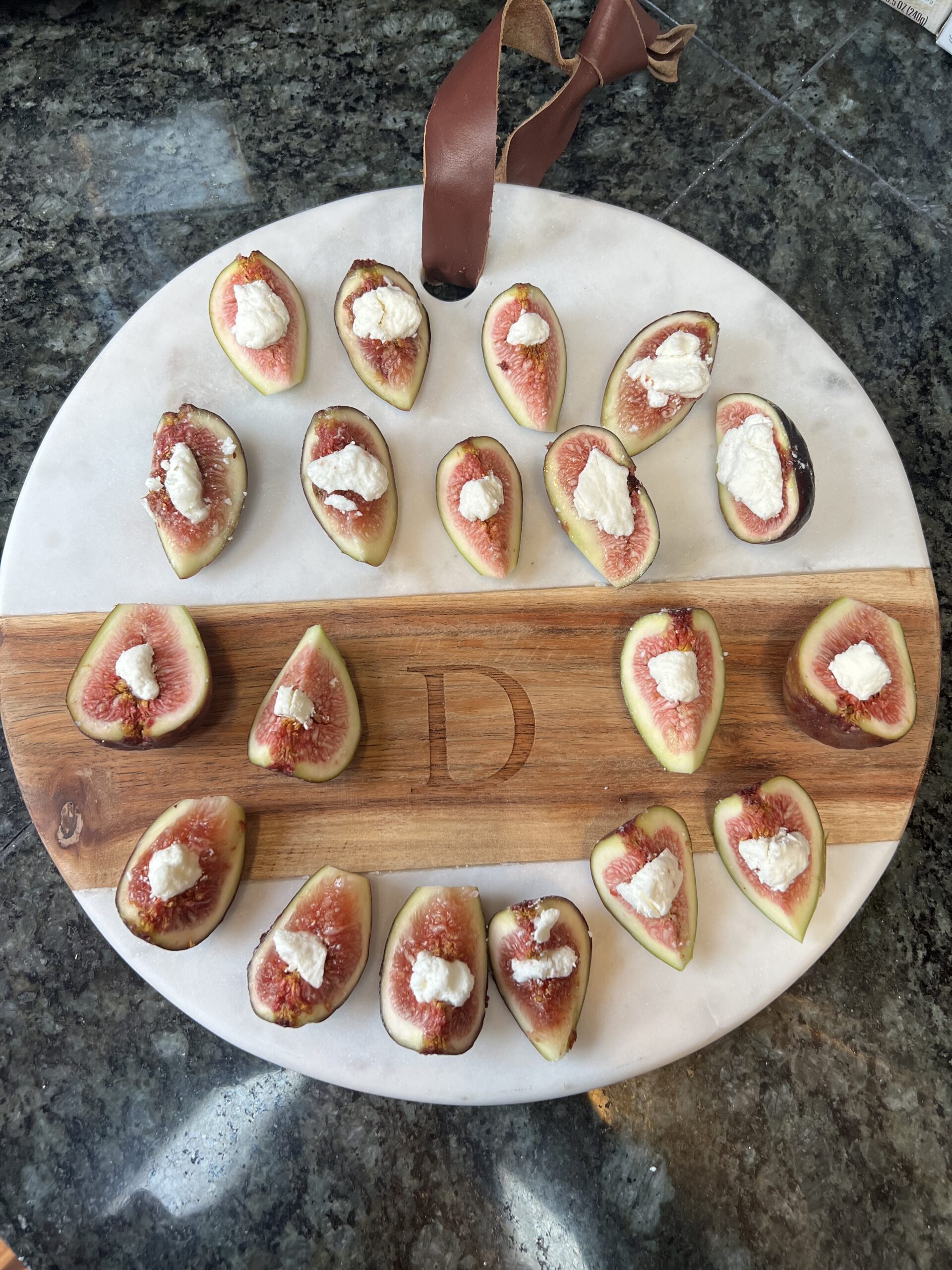A white marble serving platter topped with fresh mission figs stuffed with creamy goat cheese, garnished with toasted walnuts and a balsamic glaze drizzle—a quick 10-minute appetizer for a dinner party.