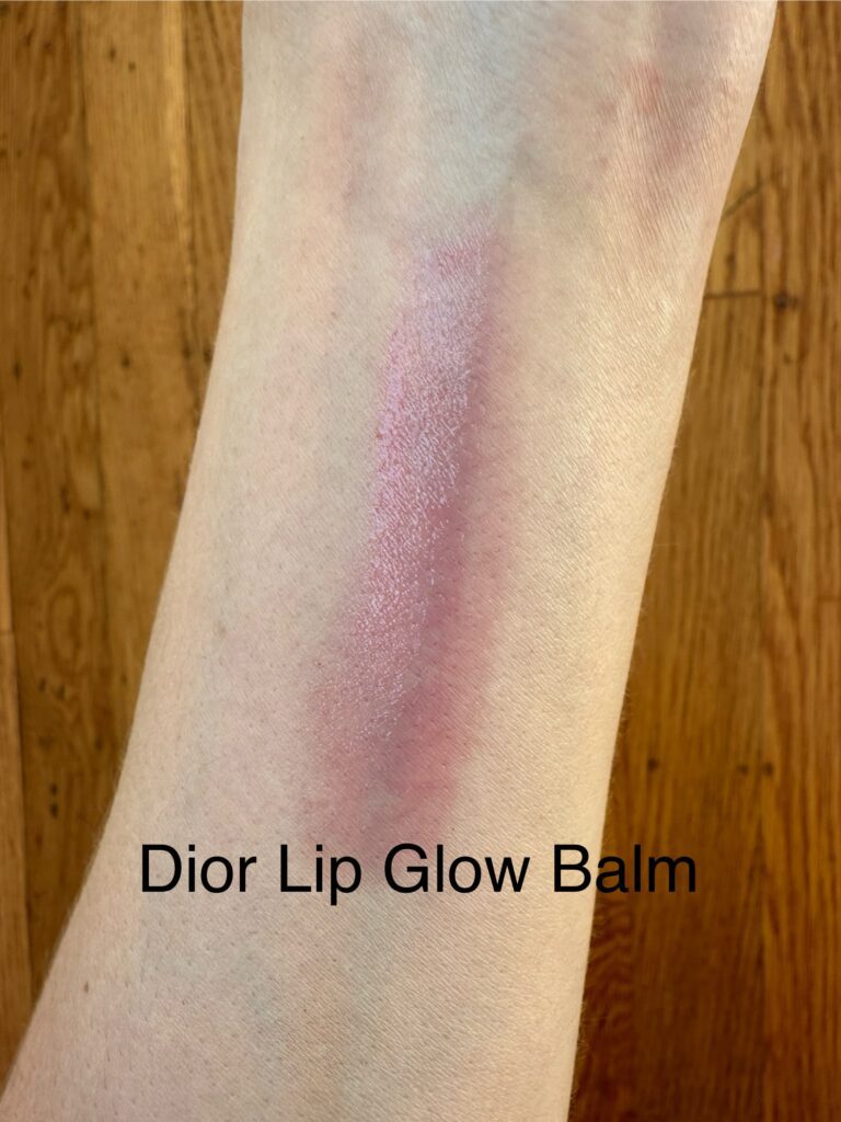 Swatch of Dior Lip Glow in Raspberry on cool-toned skin showing a sheer, buildable pink wash.