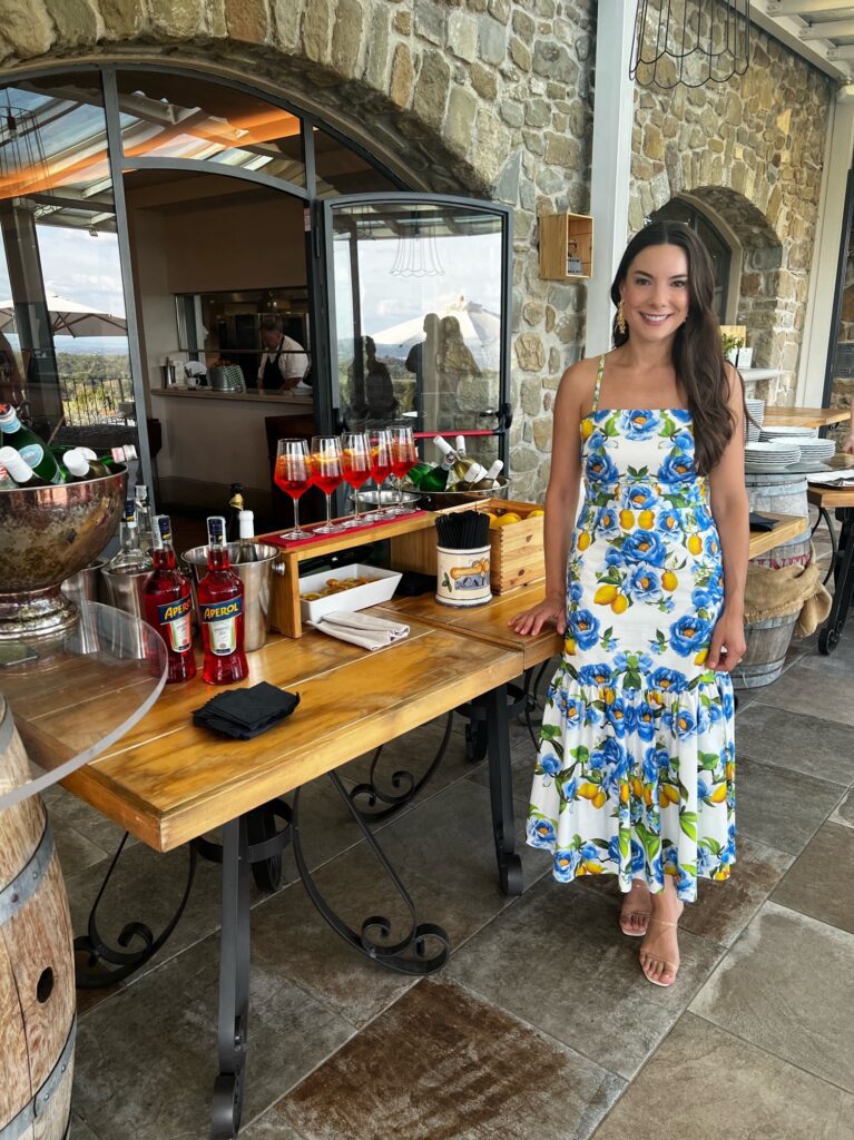 Ashley Miller Daniels standing in front of her custom Italian wedding Aperol Spritz bar in the hills of Tuscany. 