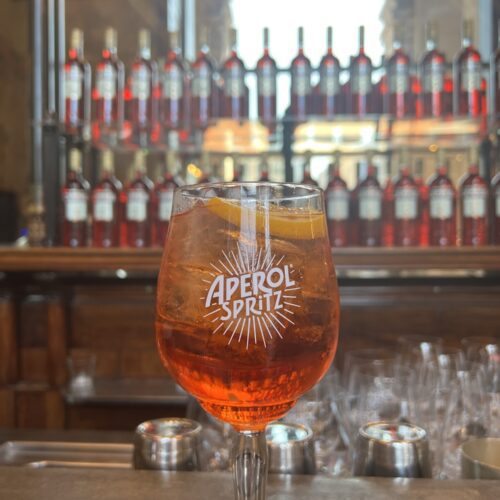 A close-up of the official 3-2-1 Aperol Spritz in a signature glass with an orange slice garnish in Italy.