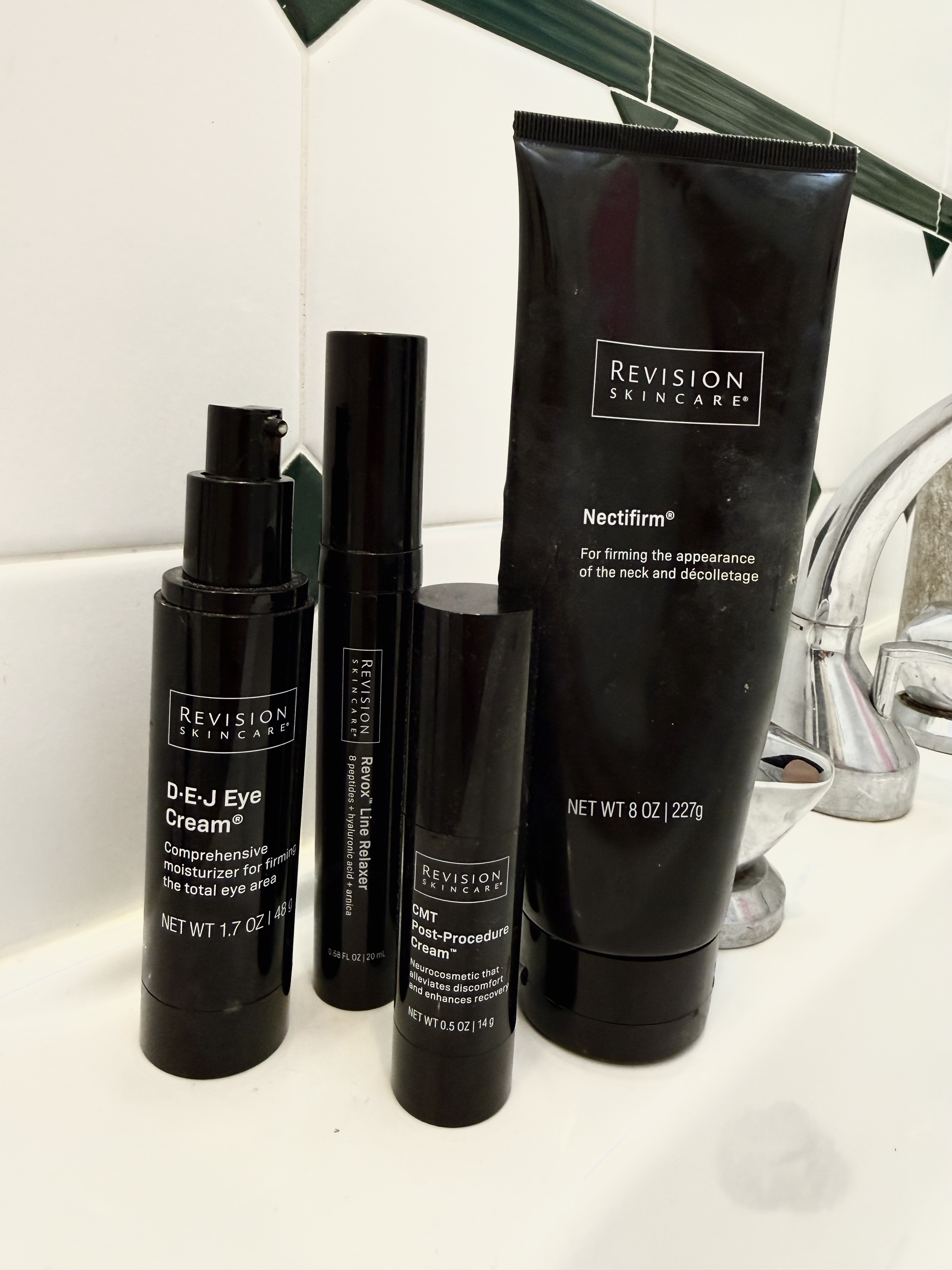 A daily medical-grade routine featuring Revision Skincare products like Nectifirm and DEJ Eye Cream, styled on a bathroom sink to show real-world product usage.